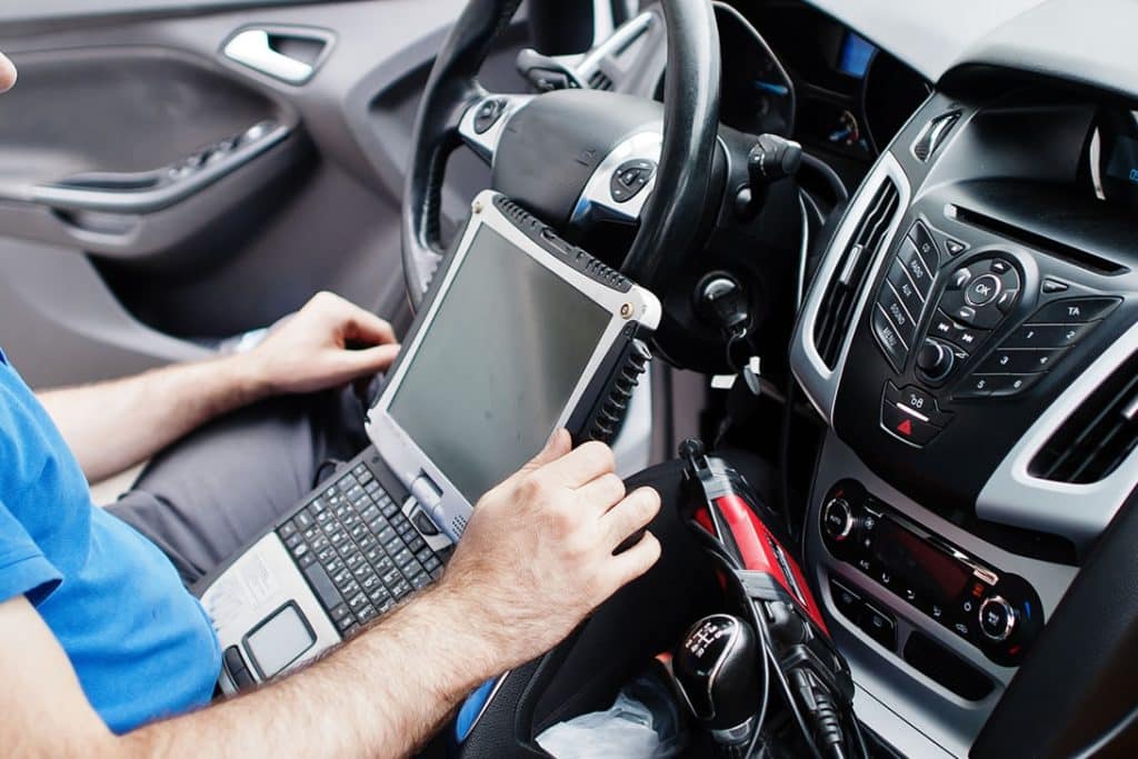Araç içinde diagnostik tablet cihazı ile DTC, arıza kodu çözümleri ve bilgisayarlı arıza tespiti uygulayan uzman teknisyen.